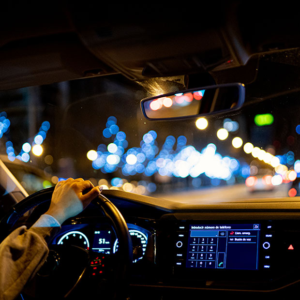 A woman driving a car at night by city.